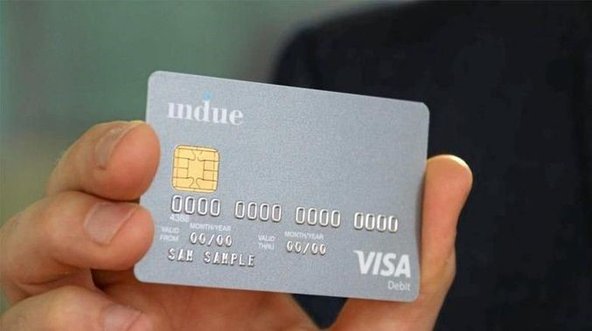 A hand holds up a sample of the cashless debit card