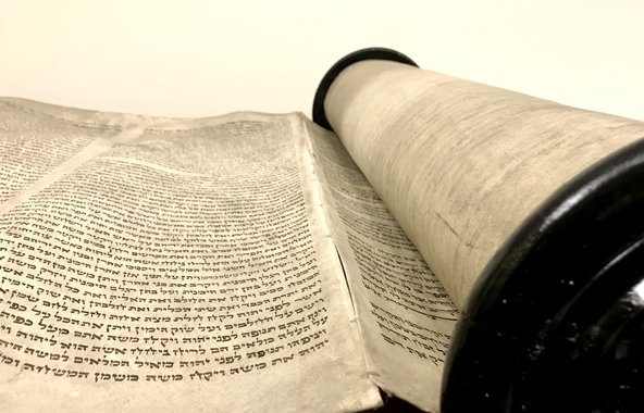 Close-up photograph of the scroll from the side with dense Hebrew text.